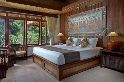 乌布缇伽姆普温泉酒店的一间卧室配有一张大床,墙上挂着一幅大画