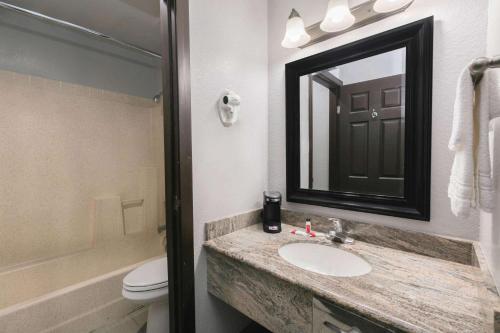 奥斯汀大学/市区速8酒店的一间带水槽、镜子和卫生间的浴室