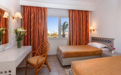 哈马马特Le Corail Appart'Hotel Yasmine Hammamet的酒店客房设有两张床、一张书桌和一个窗户。
