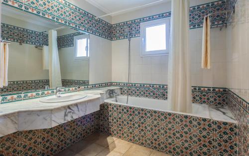 哈马马特Le Corail Appart'Hotel Yasmine Hammamet的带浴缸、水槽和镜子的浴室