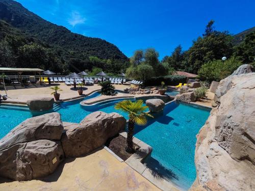 波尔图Camping Les Oliviers的度假村内拥有岩石和棕榈树的游泳池