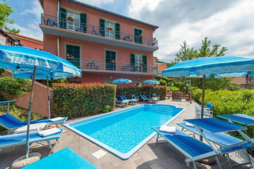 Balestrino卡德伯纳酒店的一座带椅子和遮阳伞的游泳池位于一座建筑旁边