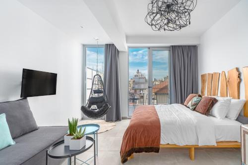 雅典Mythos Luxury Suites的一间卧室配有一张床、一张沙发和一台电视。