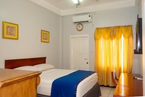 乔治敦Status International Hotel的一间卧室设有两张床,墙上挂着一个时钟。
