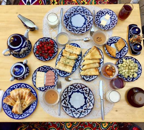 撒马尔罕Marhabo Guesthouse的一张带蓝色和白色食物板的桌子