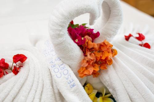 霍尼亚拉珊瑚海度假村的床上的白色毛巾,带鲜花