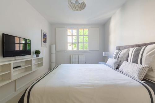 普罗旺斯艾克斯Appartement cathédrale au calme的白色卧室设有一张大床和电视。