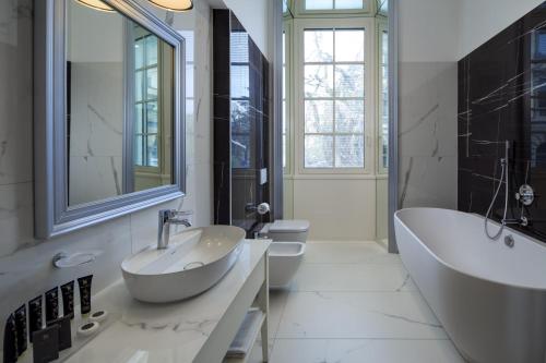 科莫Palace Hotel Lake Como的一间带两个水槽、一个浴缸和两个卫生间的浴室
