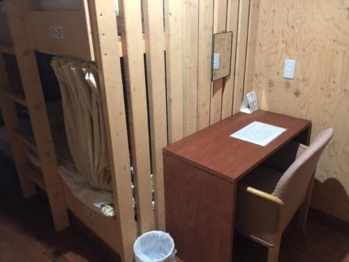 小樽Guesthouse Wanokaze mix domitory / Vacation STAY 32202的木墙旁的一张木桌和椅子