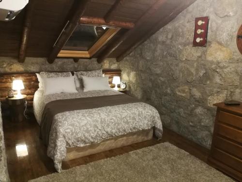 GavilanesCasa rural La Borriquita的一间卧室设有一张床和石墙