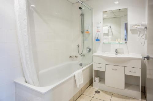奥克兰President Hotel Auckland的白色的浴室设有浴缸和水槽。