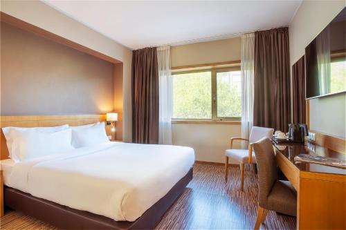 波尔图波尔图-图尔乐酒店的酒店客房设有一张大床和一张书桌。