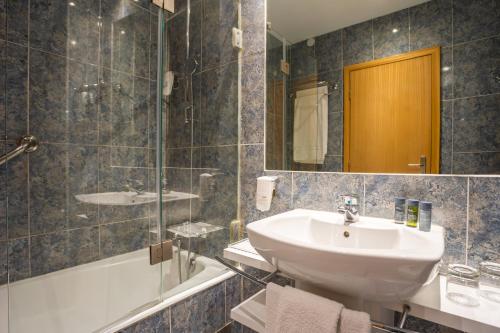波尔图波尔图-图尔乐酒店的浴室配有盥洗盆、镜子和浴缸