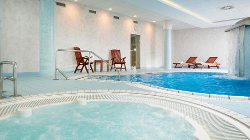 玛丽亚温泉OREA Spa Hotel Cristal的酒店客房的大型游泳池配有椅子