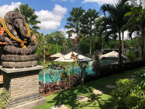 乌布巴厘岛贝图图别墅旅馆的一座位于游泳池前的雕像,