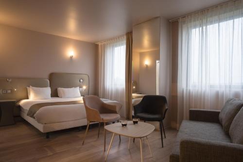 托尔西Brit Hotel Codalysa Marne la Vallée - Torcy的酒店客房配有床、沙发和桌子。