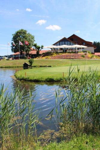 Les BoisHôtel Golf-Club Les Bois的享有带池塘的高尔夫球场的景色