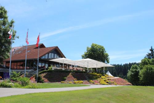 Les BoisHôtel Golf-Club Les Bois的花园内一座带两把白色遮阳伞的建筑