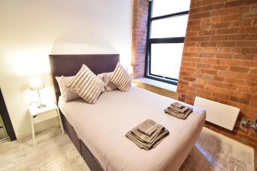 利兹Aire Apartments New York Styled Luxury Apartments的一间卧室配有一张砖墙床