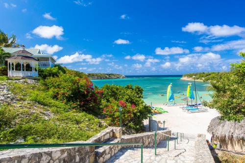 WillikiesThe Verandah Antigua - All Inclusive - Adults Only的海滩上设有椅子和遮阳伞,还有大海