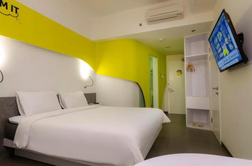 泗水耶穆尔萨利黄釉酒店 的一间卧室设有两张床,墙上配有电视。