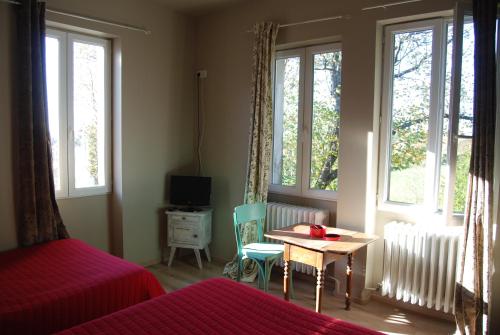 Montfaucon-en-Velay普拉坦斯酒店餐厅的卧室配有床、桌子和窗户。