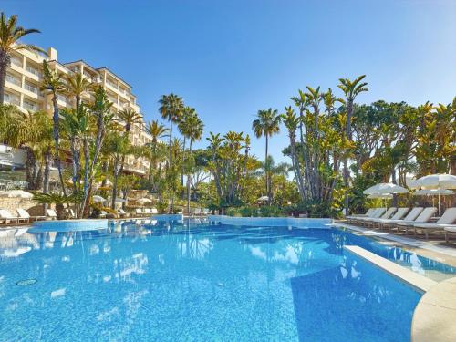 韦尔都勒博利雅公园Spa酒店的一个带椅子和棕榈树的大型游泳池