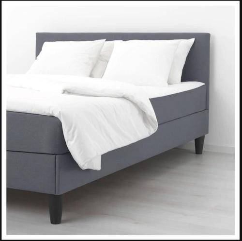 利勒斯特罗姆Sentral moderne leilighet的灰色的床,配有白色床单和枕头