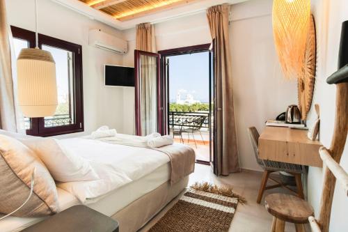 斯卡拉Aktaion Beach Boutique Hotel & Spa的一间卧室配有一张床、一张书桌和一个窗户。