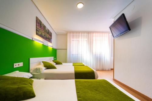 维多利亚-加斯特伊兹Hotel Centro Vitoria AutoCheckIn的绿墙客房的两张床