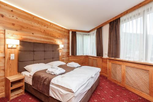 亚列姆切Baron SPA Hotel - Museum Yaremche的一间卧室配有一张带木墙的大床