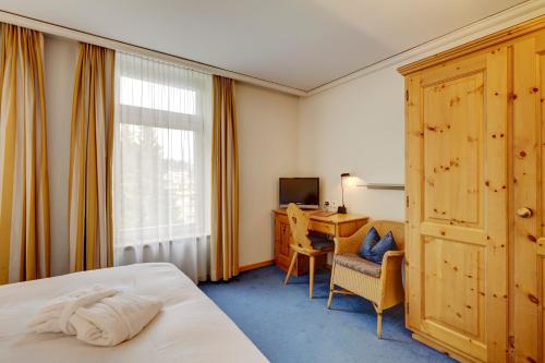 达沃斯美乐好福酒店的配有一张床、一张书桌和一扇窗户的酒店客房