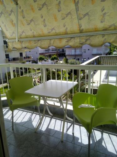 乐托卡亚ERIETTI STUDIO 3的阳台上配有一张白色的桌子和绿色的椅子