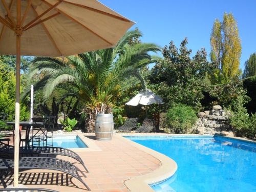 圣克鲁兹Hotel Posada Colchagua的一个带遮阳伞和桌椅的游泳池