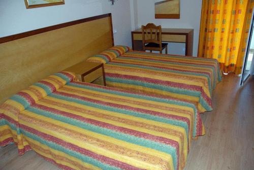 帕尔马诺瓦玛莎公寓的配有色彩缤纷的毯子的酒店客房中的两张床