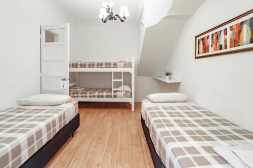 蒙得维的亚Welcome to Pocitos的配有白色墙壁和木地板的客房内的两张床