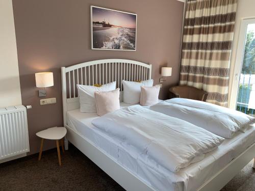 奥斯特巴特宁哈根里希特旅馆的卧室配有一张带白色床单和枕头的大床。