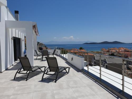 尼亚普拉莫斯Aelia Apartments的俯瞰大海的阳台的一排椅子