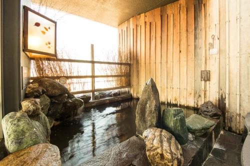 三岛市多美迎三岛酒店的客房设有带岩石的池塘和窗户。