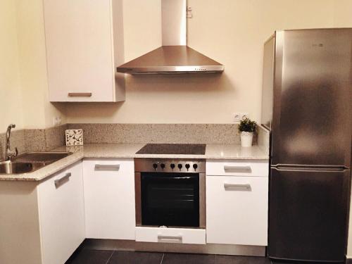 科鲁韦多Apartamento Mirador de Corrubedo的厨房配有白色橱柜和不锈钢冰箱