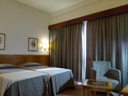 丰沙尔中心酒店的酒店客房带两张床、椅子和窗户