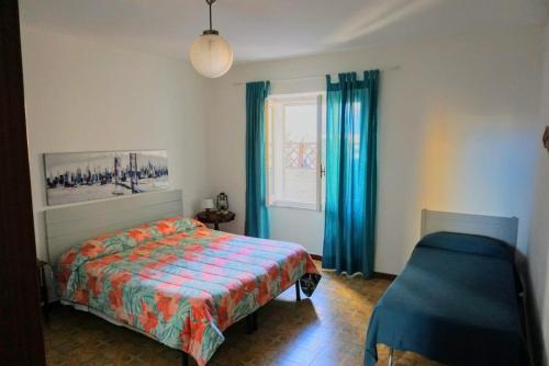 圣特雷莎加卢拉Bilocale Pascoli的一间卧室配有床和蓝色窗帘的窗户
