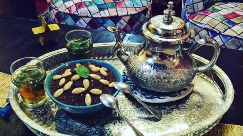塞拉Riad La Porte du Bouregreg的盘子,盘子上放着茶壶和一碗花生