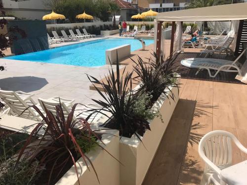 里米尼米兰聂斯酒店的一个带椅子的游泳池,一个坐在庭院里的人