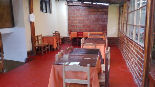 奥兰太坦波Hostal Pachar的配有桌椅的房间和砖墙