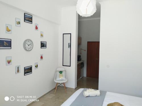 帕莱欧卡斯提撒Paleokastritsa Studios - Sun's Gift Spiros的白色的房间,墙上有椅子和时钟