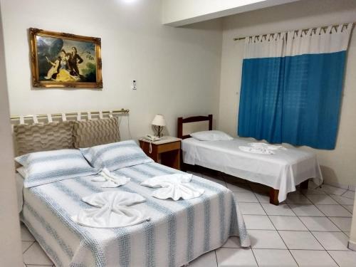 布拉干萨-保利斯塔Vinte Park Hotel的配有蓝色窗帘的客房内的两张床