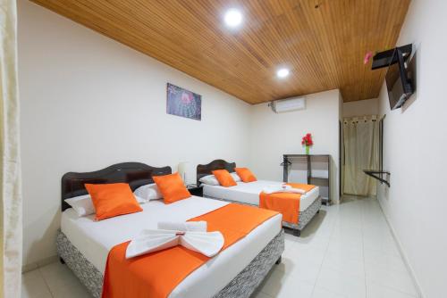 比利亚维哈Hotel Colonial Villavieja的一间卧室配有两张带橙色枕头的床