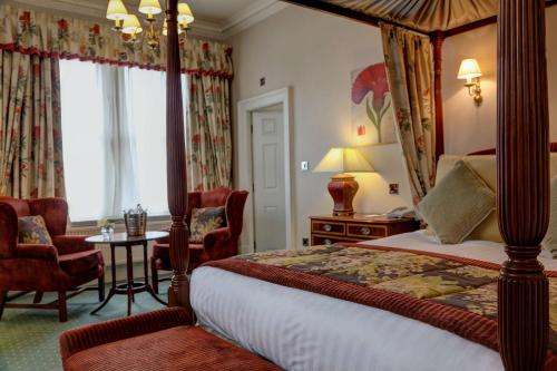 布雷得佛The Midland Hotel的一间卧室配有天蓬床和桌椅