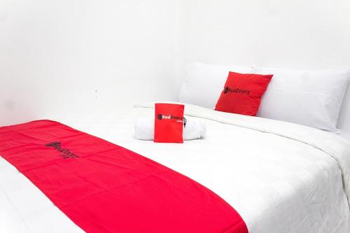 加拉旺RedDoorz @ Galuh Mas的卧室配有白色床铺上的两个红色枕头